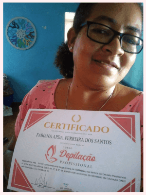 Uma mulher mostrando seu certificado de conclusão do curso de profissionalização. Ela está feliz